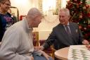 Hi Majesty spends time with a patient on a previous visit to Sue Ryder Leckhamton Court Hospice during his patronage as Prince of Wales