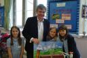 Photograph of Neil Carmichael MP with Lucy, Poppy and Isa from Class 4 Eagles, and their model of the future of Caple’s Mill.